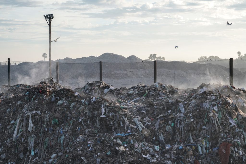 Landfill site with piles of plastic trash and birds flying overhead